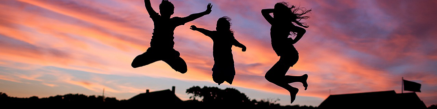 young people jumping in the air at sunset